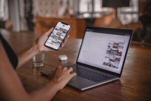 Small business owner creating social media content on phone and laptop
