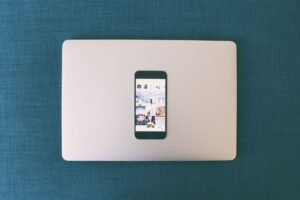 Small business owner creating social media marketing content on phone and laptop